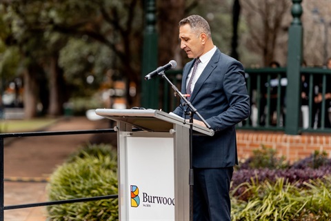 Mayor John Faker standing at a lecturn speaking into a microphone at Burwood Park
