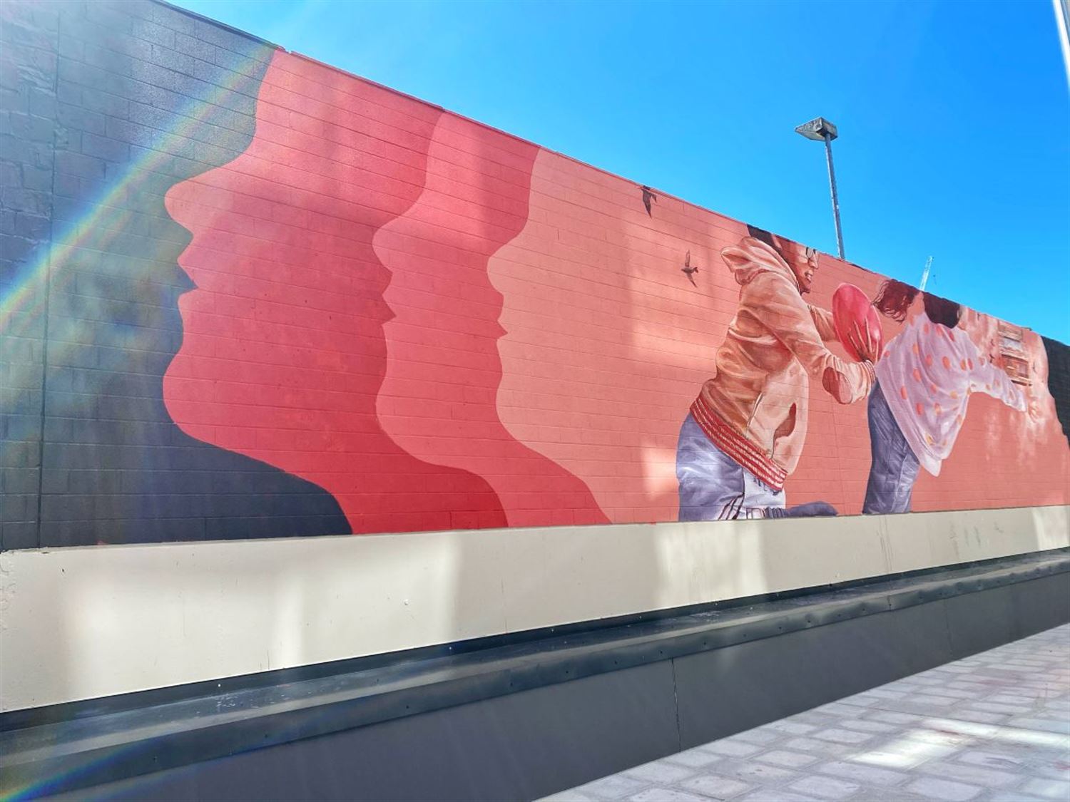 wall mural of two children against a pink backdrop playing ball